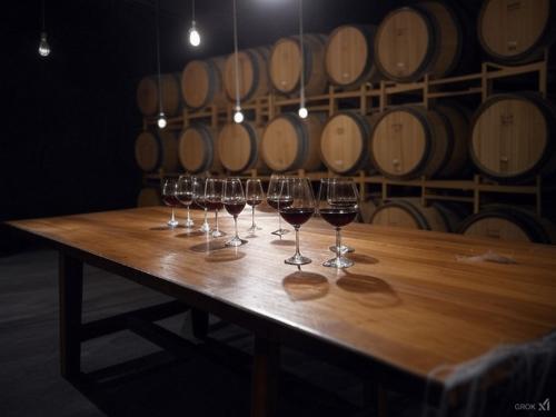 A winery table with glasses set up for a tasting surrounded by barrels