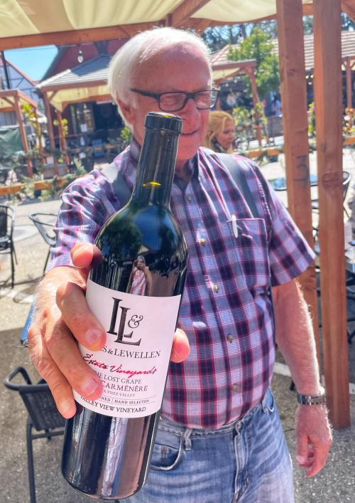 Louis Lucas holding a bottle of Carmenere wine for Free Tasting Friday at Lucas & Lewellen Vineyards and the Toccata Tasting Room