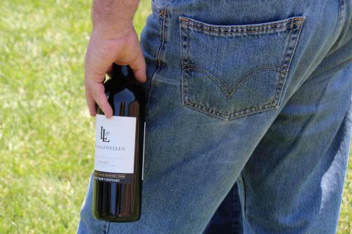 A photo of Lucas & Lewellen Tasting Room Manager Andy in jeans holding a wine bottle A photo of Lucas & Lewellen Tasting Room Manager Andy in jeans holding a wine bottle