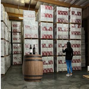 Woman standing in front of case of wine - Wine Pull warehouse wine sale