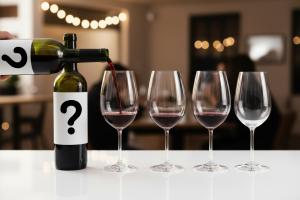 4 glasses of wine with two white labels with question marks for a blind tasting